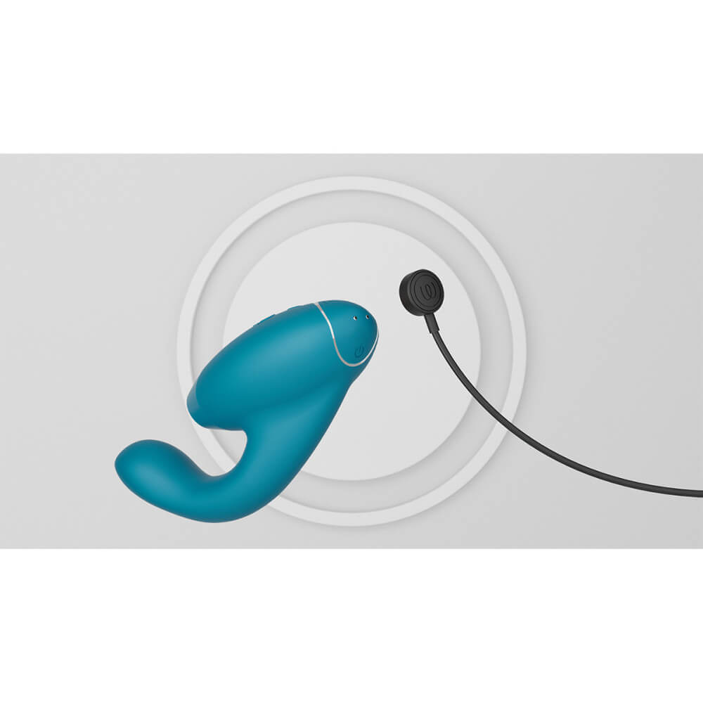 The Womanizer Duo 2 with the bottom of the toy facing the camera. The magnetic charging cable is poised near the bottom of the toy, ready to plug it in for charging. | Kinkly Shop